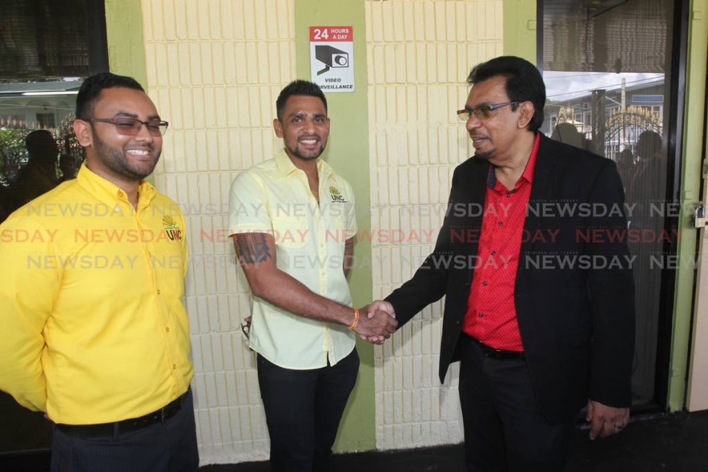 Local Government Minister Kazim Hosein greets UNC candidates for Les Effort East and West, Sachin Maharaj and Rishi Balramsingh as they waited to file their nomination papers on Rushworth street, San Fernando, on Monday. - Lincoln Holder