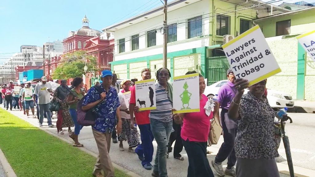 Protesters with placards voice their sentiments against the LATT outside the Hall of Justice yesterday..  - Tyrell Gittens