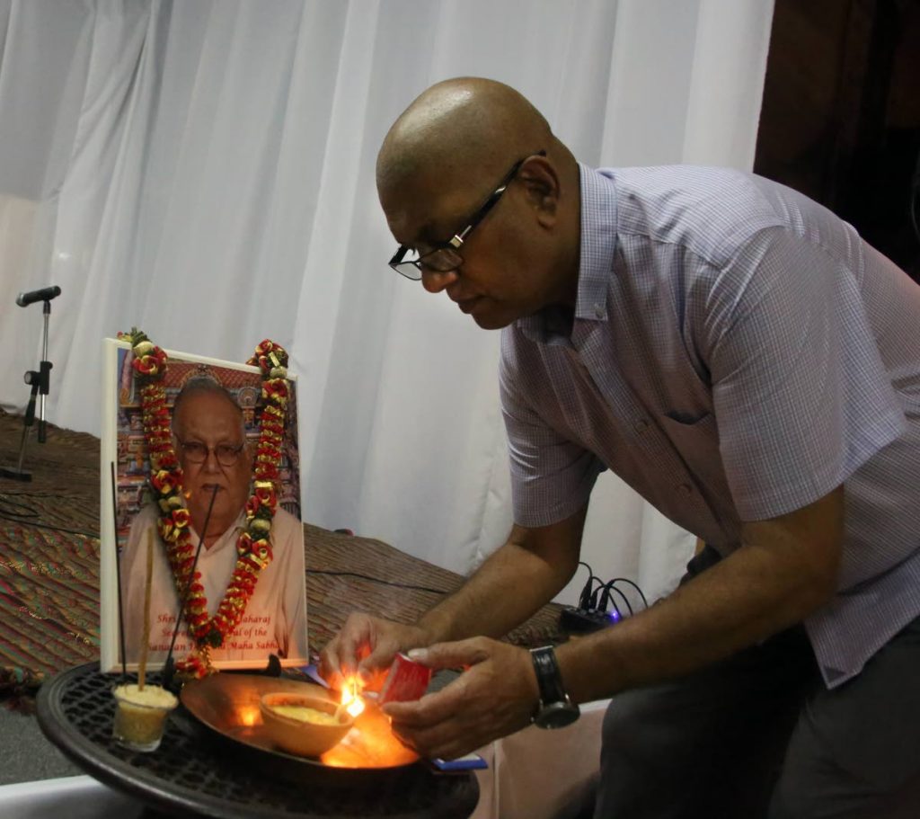 Vijay Maharaj lights a deya before a protrait of his father Satnarayan 