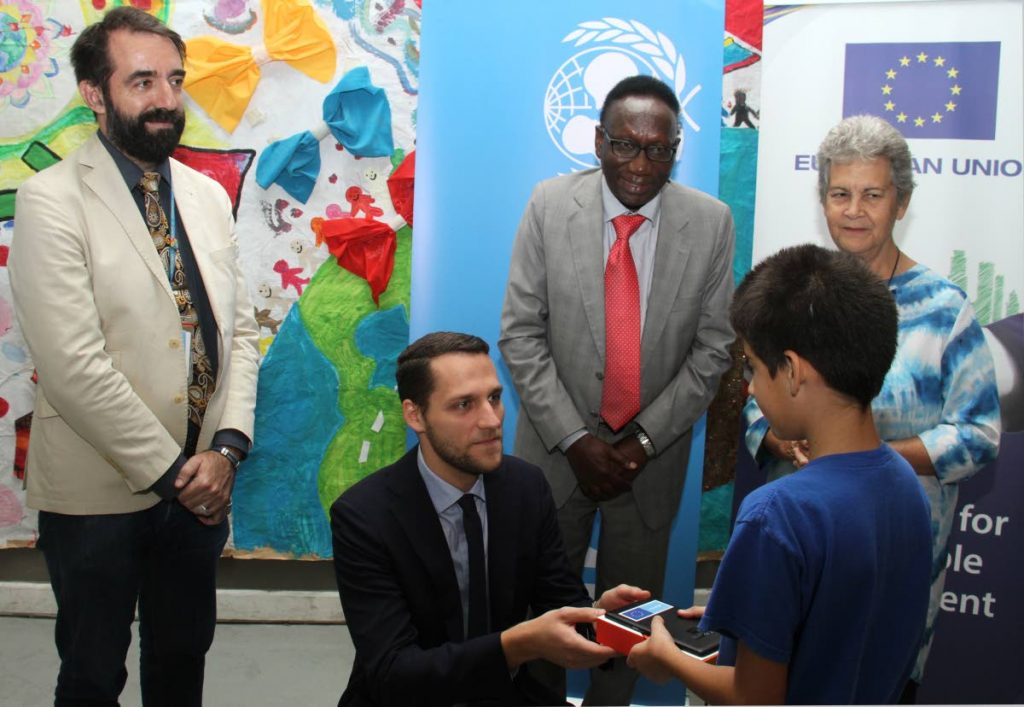 BRIGHT FUTURE: Junior professional in the political section of the European Union Delegation, Olaf Arnicans, presents a child with one of the tablets at the Living Water Child Friendly Centre in Maraval on Monday. Looking on are Ruben Barbado of the UNHCR, Dr Aloys Kamuragiye of UNICEF and Living Water Community co-founder Rhonda Maingot. PHOTO BY AYANNA KINSALE - Ayanna Kinsale