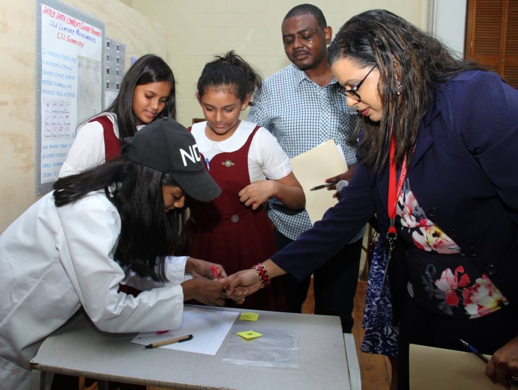 Christianna Boodoo of Holy Faith Convent, Couva demonstrates the forensic process to judges during the Math fair at the JFK Auditorium, the University of the West Indies (UWI) on Friday while her teammates Angelina Darsansingh and Alana Lutchmansingh looks on. - AYANNA KINSALE