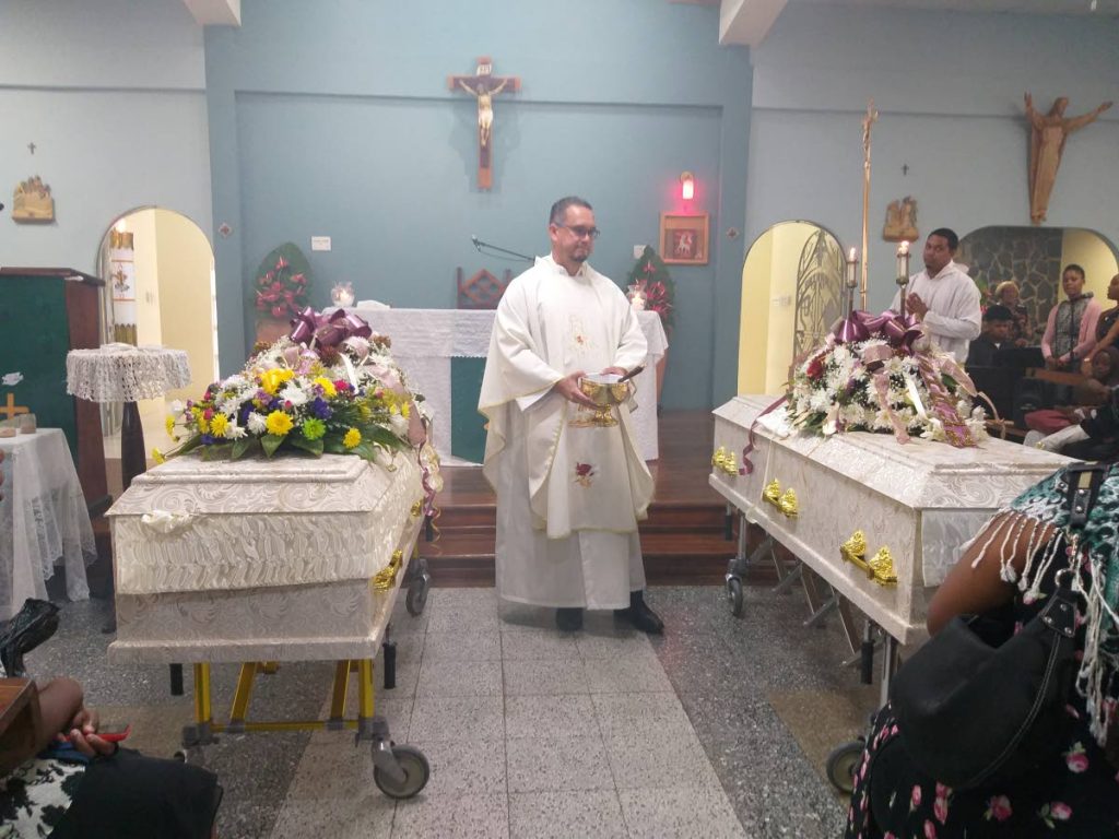 Fr Gerard Tang Choon performs final rites for murder victims Marsha Joseph and her son Shawn during their funerals at Mary Immaculate Queen of the Universe RC Church, Bourg Mulatresse, lower Santa Cruz on Saturday.  - Tyrell Gittens