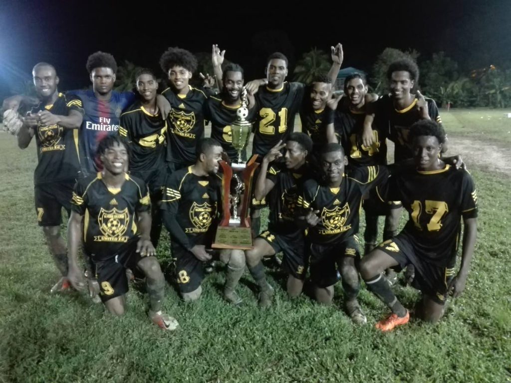 Dream Team players celebrate with the trophy after beating Pinto United in the Fishing Pond Football League final at the Manzanilla Recreation Ground on Sunday. - 