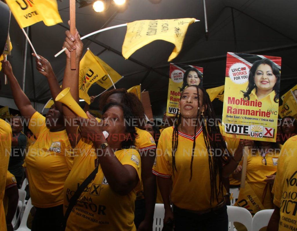 UNC supporters, some blowing horns, wave flags and posters of local government candidates at a meeting in Rousillac on Friday night. - Vashti Singh