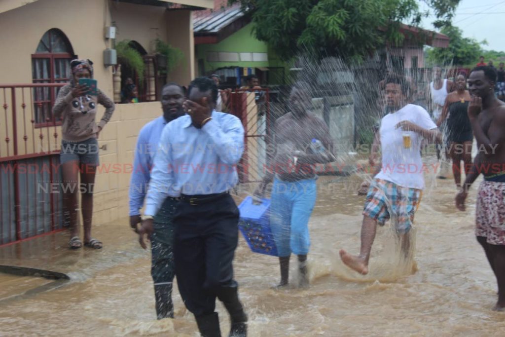  MP for Laventille West Fitzgerald Hinds covers his face as he is drenched with a kick of flood waters, along with councillor for the area Akil Audain, during a visit to Beetham Gardens in 2018.