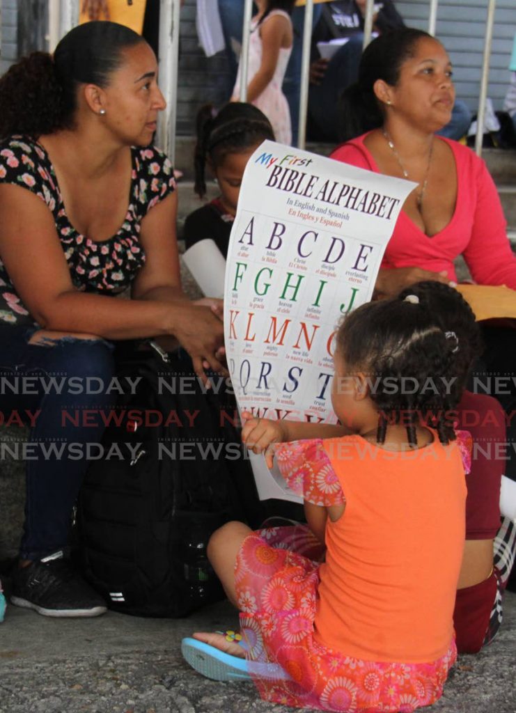 In this June 14 file photo a Venezuelan child reads an alphabet card during the registration of migrants at Queen’s Park Oval, Port of Spain. - Angelo Marcelle