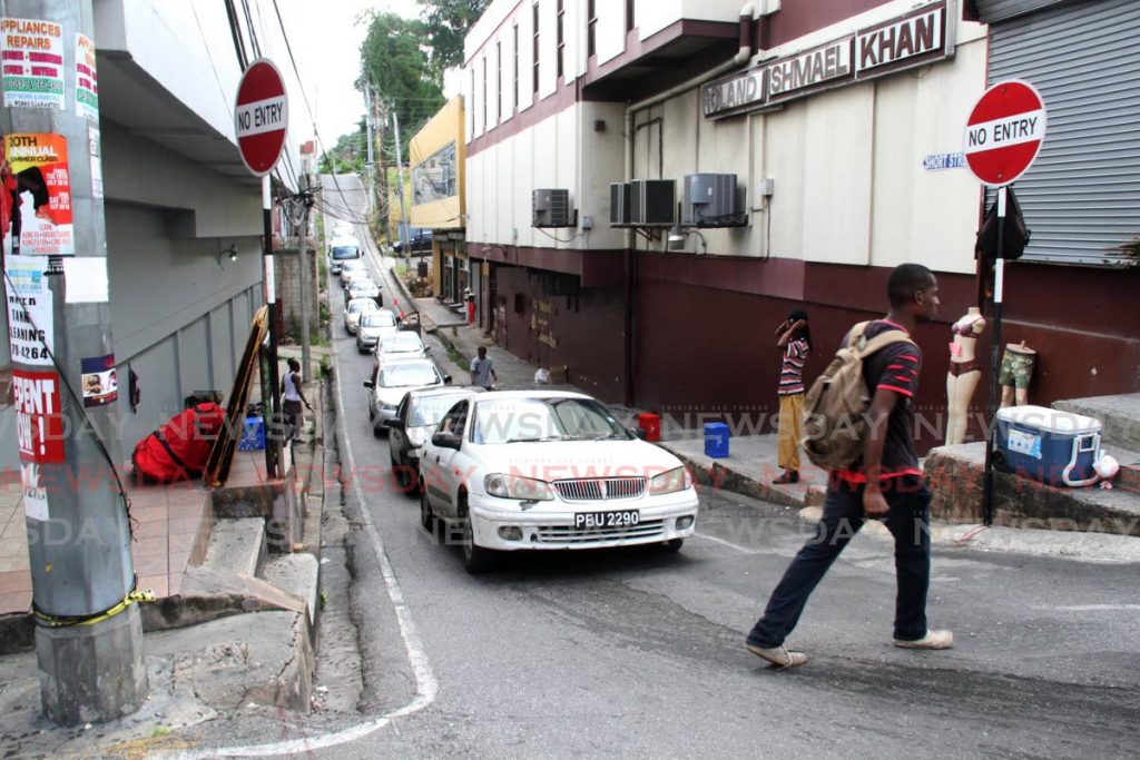 Vehicles pile up on the steep hill on Short Street , San Fernando as pedestrians have to walk across on on High Street . - Vashti Singh