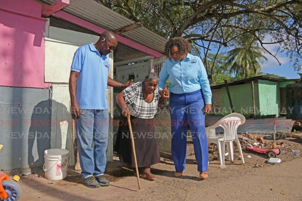 In this November 11 file photo MSJ area coordinator Theophilus Henry and local government candidate for Erin Crystal Bernard assist Erin village Annie Harbet during a walkabout. The MSJ is contesting electoral districts in five corporations. - Marvin Hamilton