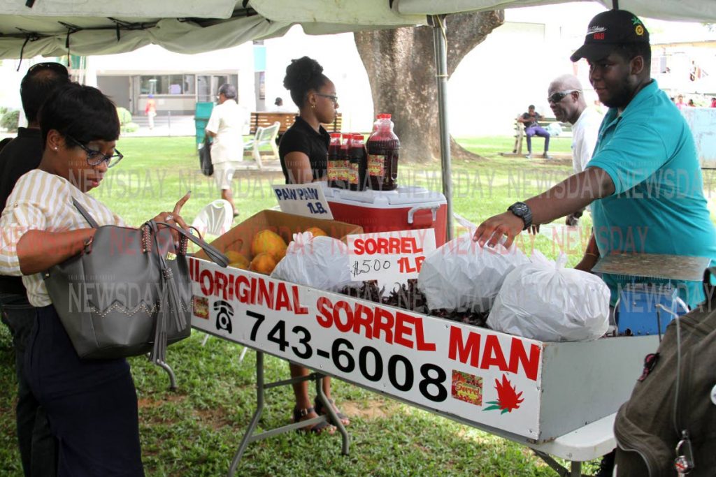Customers get their seasonal fruit and drink from ‘the Original Sorrel Man’ at the UWI farmers and entrepreneurial market - ANGELO_MARCELLE