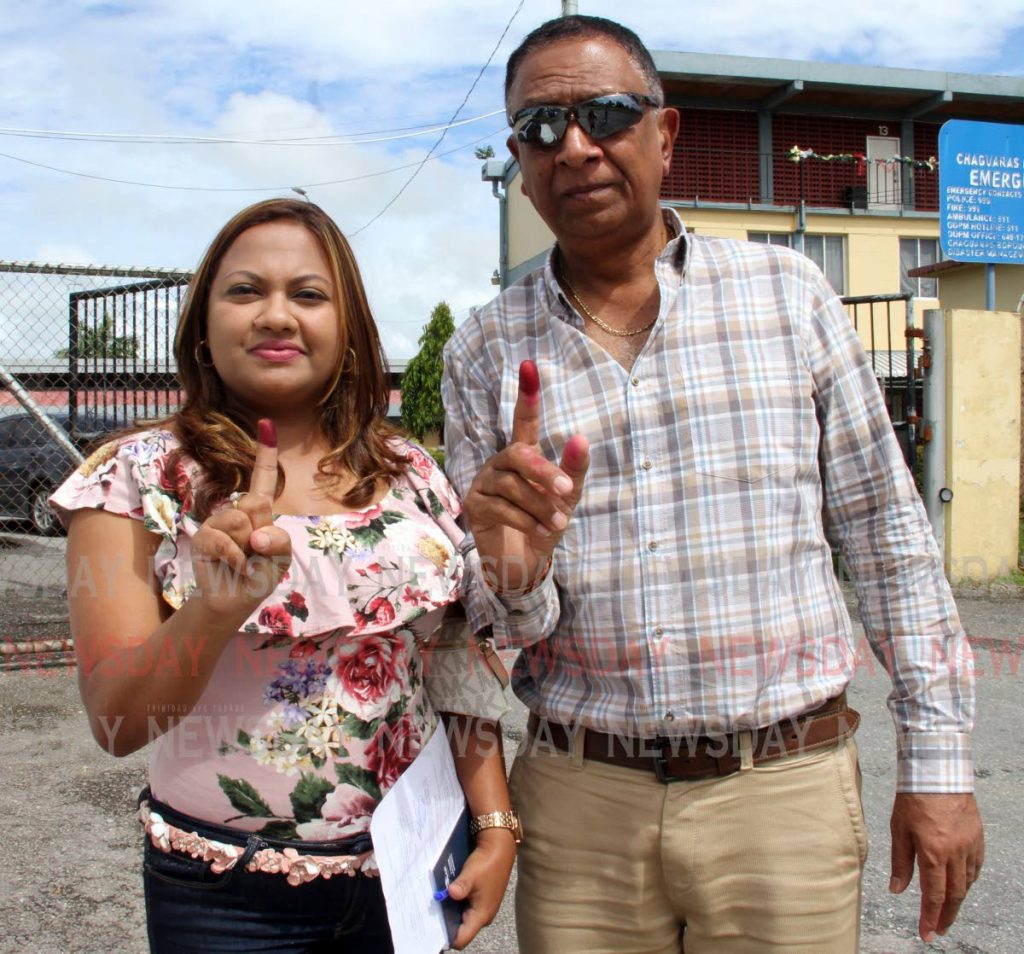 Mayor Gopaul Boodan, right, and niece Debbie Boodan show off their index fingers after voting at the Chaguanas South Secondary School on Monday. - Vashti Singh