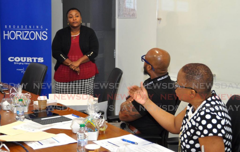 Michelle Thompson, right, regional manager, Courts, Unicomer; gives some feedback to Andrea Graham-Hosein, who manufactures ice cream and cakes through her company It’s Ummm....Scrump-ti-ta-tious, as Devon Romero, director, consumer finance, Unicomer listens in. - 