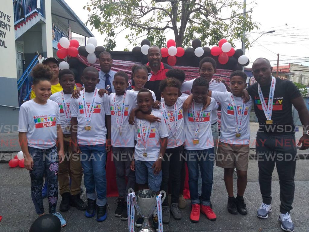  Members of the Arima Boys’ Govt School football team smile as they display their 2019 Scotiabank Concacaf NextPlay winner’s trophy. Playing with the team, for the duration of the competition was Kertiesha Joseph (L) of Maloney Govt Primary School. Present at the ceremony to honour the team was former national footballer Clayton Ince (center back-row).  - Tyrell Gittens 