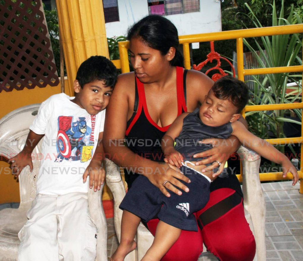 Marciela Navarro holds her one-year-old Samuel Velásquez alongside her son Christhofer Pineda, six, in an apartment where she gave shelter to two families during flooding at Puzzle Island, Penal. Photos by Vashti Singh - Vashti Singh