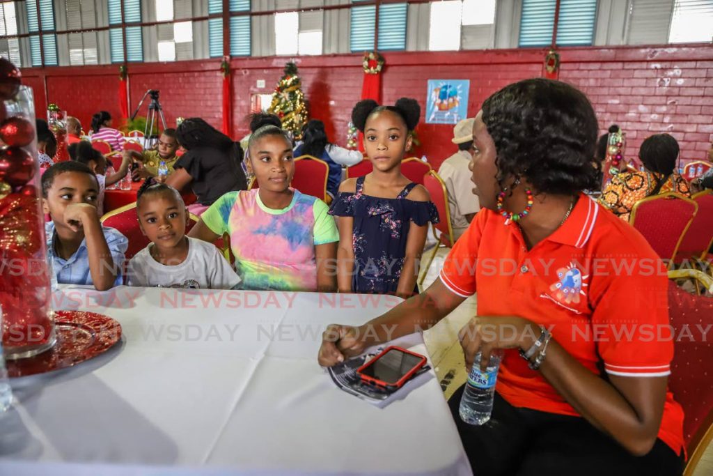 REACH 'N Inc's Adalia Mayers, right, talks with children from Diego Martin at the NGO's Victims to Victors Luncheon, part of its Let Love Flow programme at the Woodbrook Youth Facility in Port of Spain on Sunday. - JEFF K MAYERS