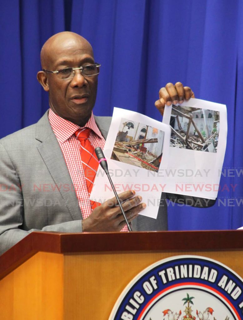 Prime Minister Dr Keith Rowley shows photos comparing what President's House looked like when the roof collapsed, and after it was restored.   PHOTO BY ROGER JACOB - ROGER JACOB