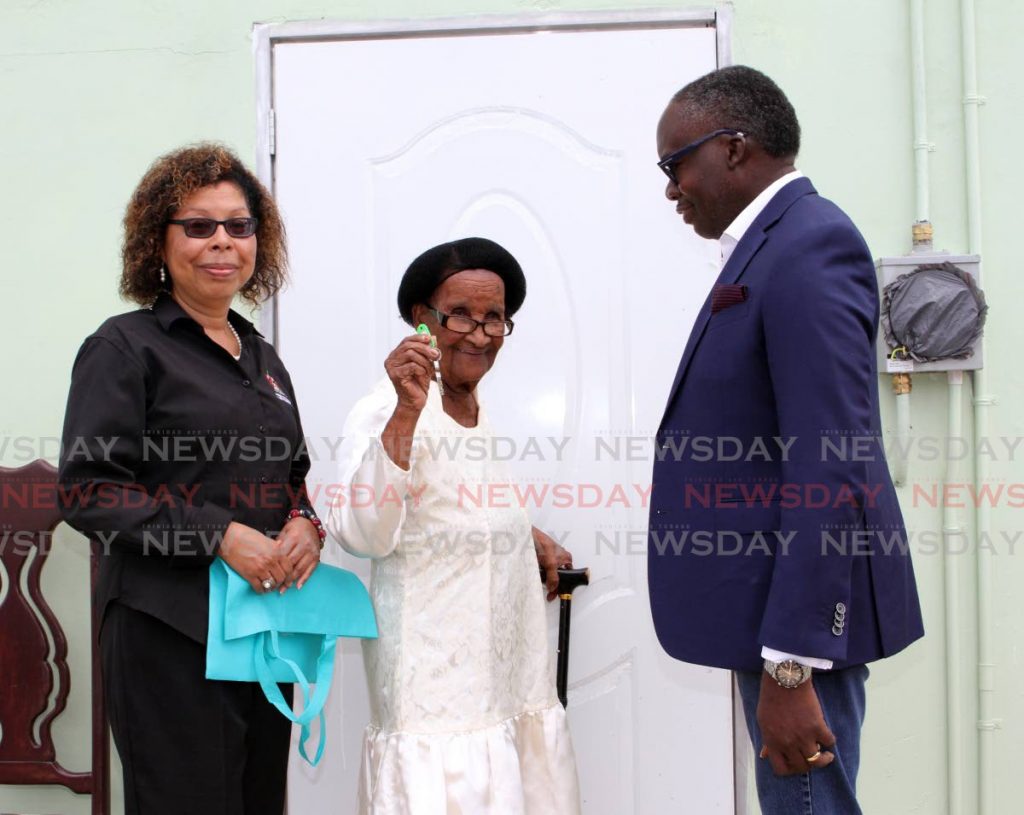 Frederica  Tyson 91, shows the key to her newly refurbished home in Talparo on Friday. It was officially presented to her by The Ministry of Housing and Urban Development Permanent Secretary Simone Thorne-Mora, left and La Horquetta/Talparo MP Maxie Cuffie.  Photo by - ANGELO MARCELLE