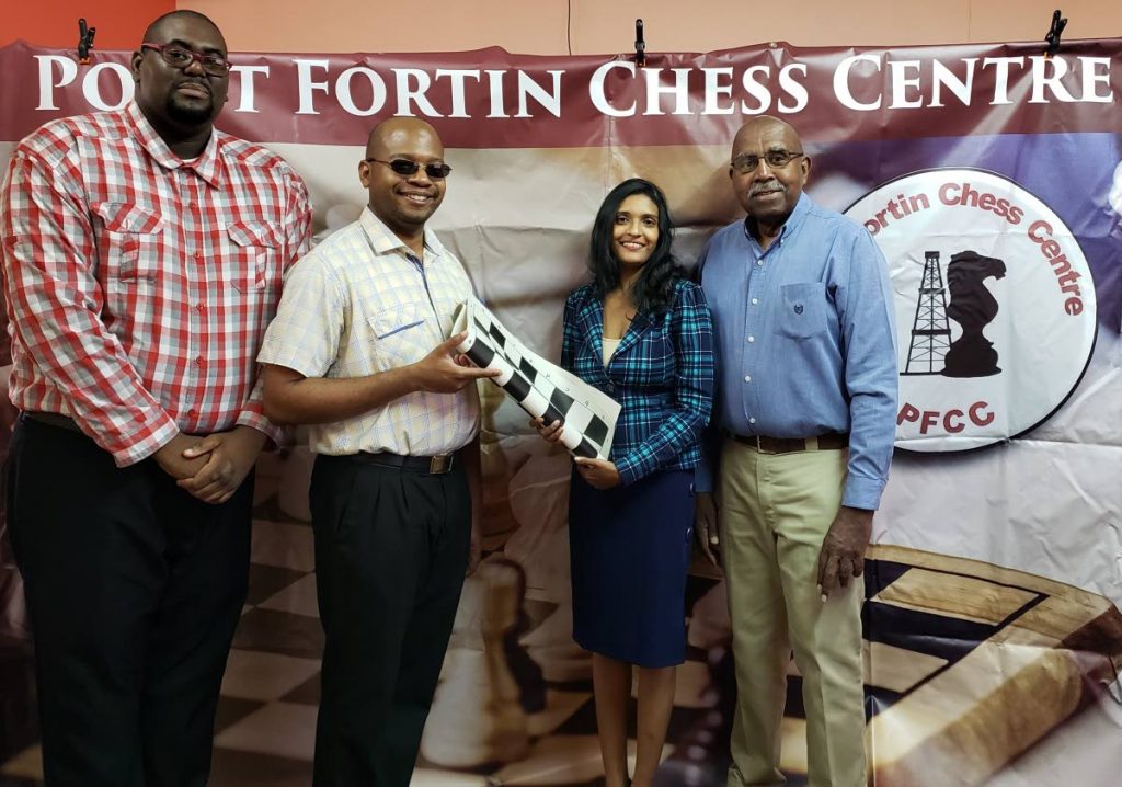 Dr Jo-Anne Sewlal, second from right, and Raymond Aaron, right, co-founders of the NGO Creative Minds Development Initiative and the Point Fortin Chess Centre, are seen making the presentation to Maxx Creese, second from left, and Kevon Prince of Point Fortin West Secondary School. - 