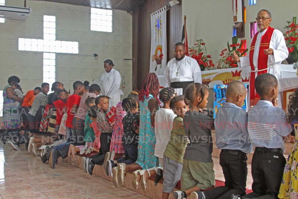 Rev Wayne Maughan and Rev Hakim Mark bless children and their Christmas gifts at St Paul's Anglican Church, San Fernando on Saturday. - Marvin Hamilton