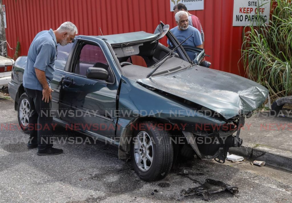 Anthony Persad looks into the car his son was driving when he crashed while driving at St Lucien Road, Diego Martin on Saturday night.  PHOTO BY JEFF K MAYERS - JEFF K MAYERS