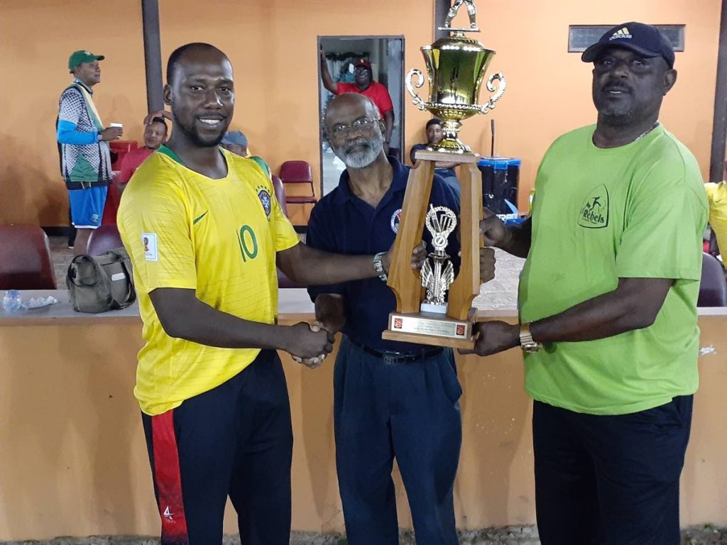 Marlon Richards, left, captain of the Umpires team collects the challenge trophy from Kelvin Williams, right, and Arjoon Ramlal on Friday. Umpires beat the Rebels team of ex-national players in the annual T20 cricket match. PHOTOS COURTESY TTCB - TTCB