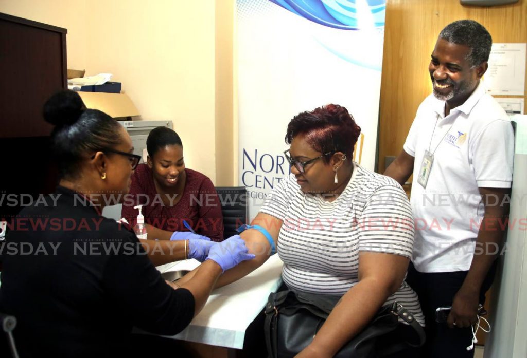 North Central Regional Health Authority (NCRHA), corporate communications manager Peter Neptune, right, looks on as, from left, nurses Stacy Charles and Darleen Thomas draw a blood sample from Newsday reporter Marlene Augustine during the authority's Ready for the Road drive, in which media workers were given a free medical checkup at the St Joseph Health Centre, Mt Hope. - SUREASH CHOLAI