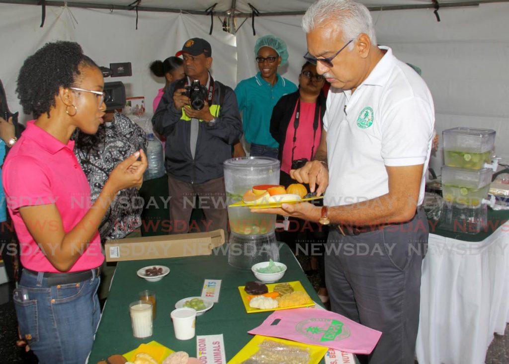 Minister of Health Terrence Deyalsingh holds a proper serving of fruit as nutritionist Dr Candace Simpson-Smith speaks about food portion sizing at the Eastern Regional Health Authority's (ERHA) breast cancer awareness drive at the St Francis of Assisi RC Church, Sangre Grande, Wednesday. - ROGER JACOB