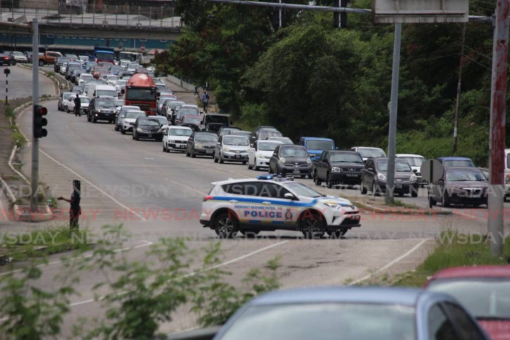 Traffic slows to a crawl as officers survey the scene of a shootout between police and three gunmen on the Eastern Main Road in Laventille on Wednesday afternoon. The gunmen, who escaped capture at the time, were believed to have killed two men and wounded a woman a few minutes earlier. - Sureash Cholai