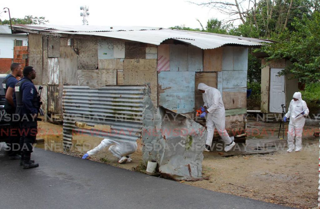 Crime scene investigators search around the house at Demerara Road, Wallerfield where three men were killed early Thursday morning.  - ROGER JACOB