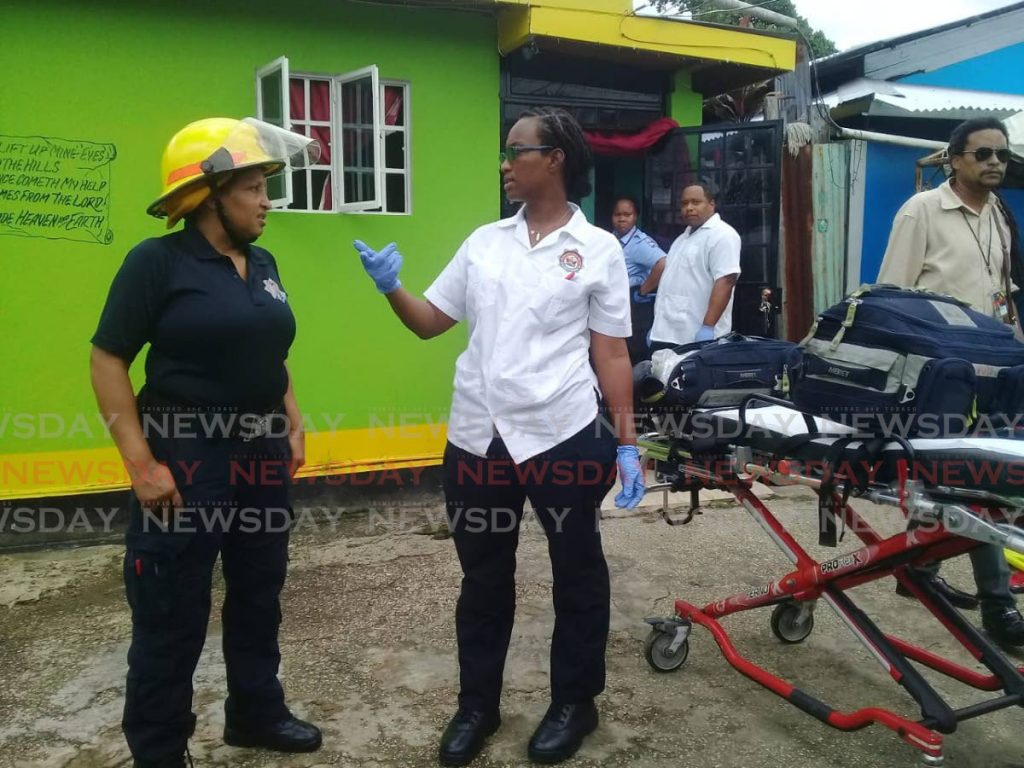 A fire officer speaks to a paramedic at a fire along 25th Street, Phase Four, Beetham Gardens, on Friday afternoon.  - Shane Superville