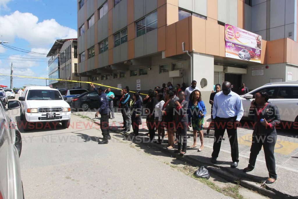 Colleagues of Naiee Singh  who was employed at Venture Credit Union in Couva, line the roadway as undertakers remove the body of her body after she was shot and killed by her husband Roger Singh who then took his life outside the credit union on Monday. - Lincoln Holder