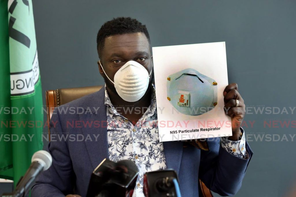 PSA president Watson Duke wearing a dust mask, saying it will offer no protection against the coronavirus, and holding a photo of the mask he wants the Government to provide for those at risk.  PHOTO - Sureash Cholai