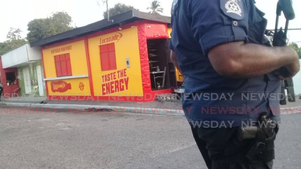 A policeman stands guard at the scene of a shooting in which one man was killed and two others wounded at a parlour at Harding Place, Cocorite, on Friday. - SHANE SUPERVILLE