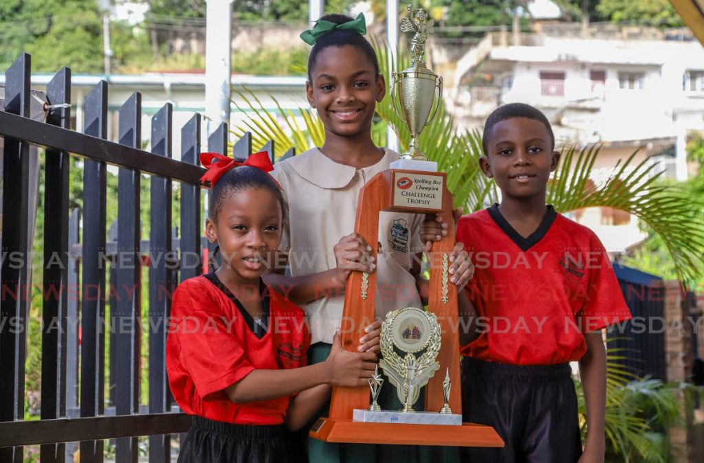 Spelling champs: From left, Amiah Adams, seven; Kieyanna Seechan, 11; and Aldrin Johnson, nine, show off their Spelling Bee challenge trophy at the St Peters RC Primary School, Point Cumana. - JEFF K MAYERS