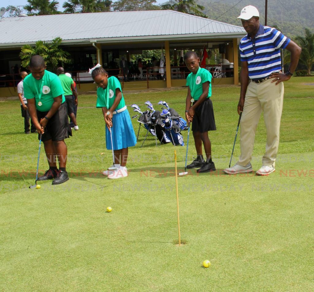 Prime Minister Dr Keith Rowley, looks on as top golf achievers; L-R, J'quan Warner of Carenage Boys Government School, Nyomi Roberts of Deigo Martin Girls RC School and Kiwani Quamina of Pt Cumana RC School, showcase their golfing skills, at the prize giving ceremony of the Junior Golf Programme, Chaguaramas Golf Course, on Friday. PHOTO BY ROGER JACOB.  - ROGER JACOB