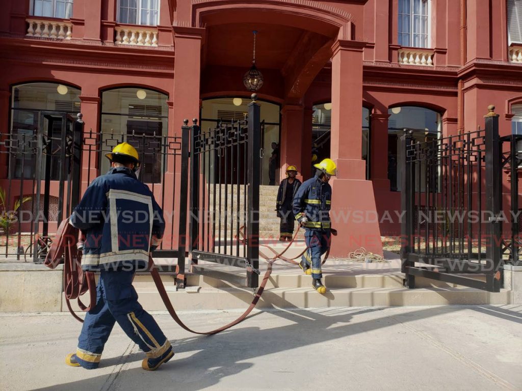 Fire officers respond to an alarm at the Red House on Abercromby Street, Port of Spain, Sunday. After a thorough search, no fire or smoke was found and the building was declared safe. - ROGER JACOB