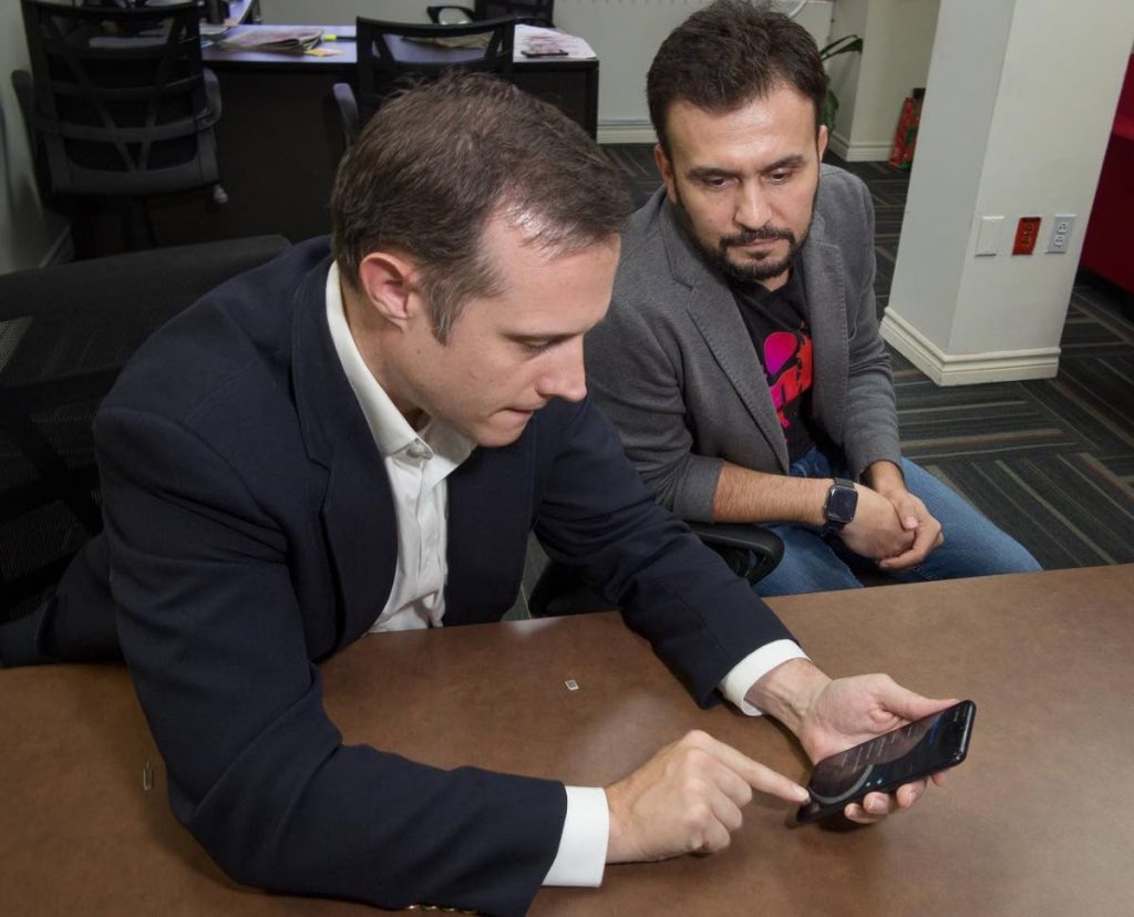 Abraham Smith and Jabbor Kayumov prepare a new smartphone to demonstrate the notification system. Photo by Mark Lyndersay. - Mark Lyndersay