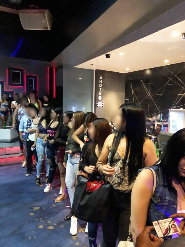 NIGHT CLUB RAID: This photo, provided by police, shows a line of women believed to be from Venezuela who were rounded up by police during a raid at a popular night club in Woodbrook during the early morning hours on Monday.  - 