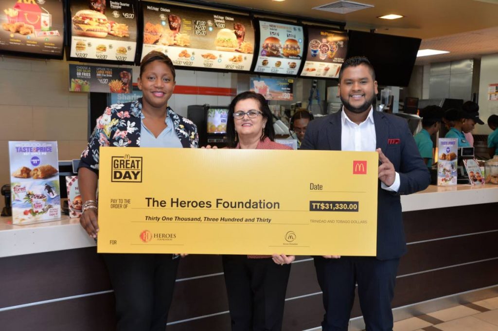  Kalifa Duncan, left, McDonald’s market manager hands over the Great Day cheque to former CEO Najette Abraham and incoming CEO Lawrence Arjoon of The Heroes Foundation.  - 