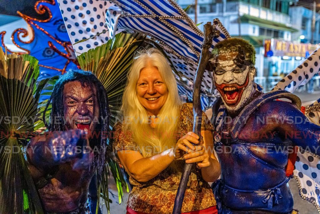 Next Level Devils Steffano Marcano (left) and Sterlyn Pierre (right) take photos with a tourist at the end of the 2020 NCC Traditional Individual Competition at Adam Smith Square, Port of Spain on February 18. - JEFF K MAYERS