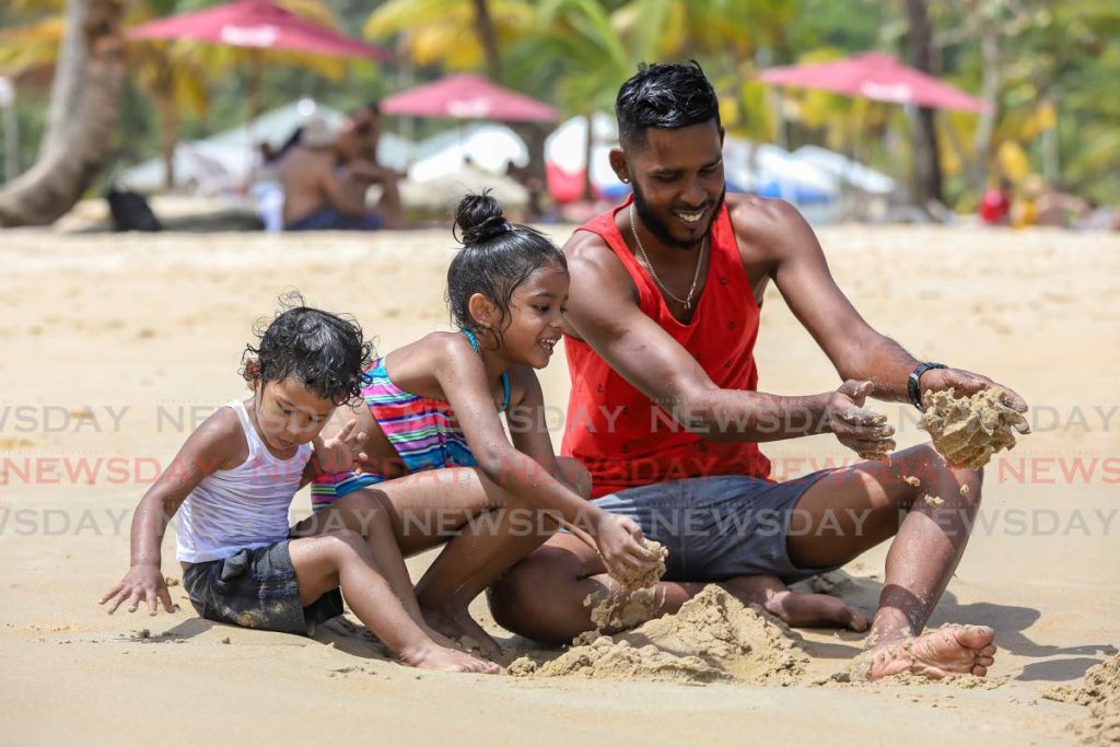 BEACH LIME: Afraz Ali plays on the sand with his children on Ash Wednesday at Maracas Bay. - JEFF K MAYERS