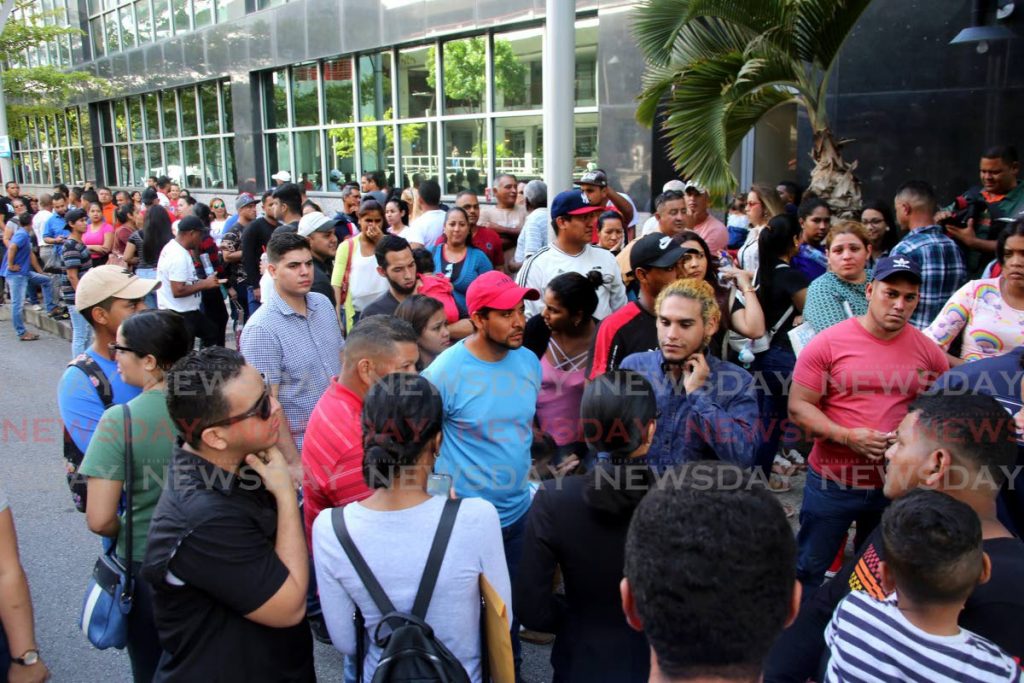 In this December 19, 2019 file photo Venezuelans wait to receive registration cards at the Immigration Division, Ministry of National Security, Richmond Street, Port of Spain. - SUREASH CHOLAI