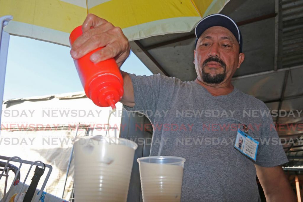 
Alberto Ramón Piñero adds condensed milk to his chicha drinks at his stall in Chaguanas. - Marvin Hamilton