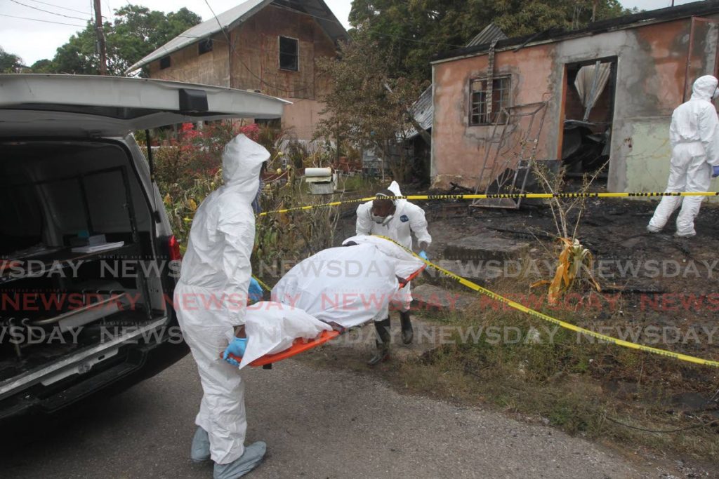 Undertakers remove one of three bodies found in house destroyed by fire in Guapo. - LINCOLN HOLDER