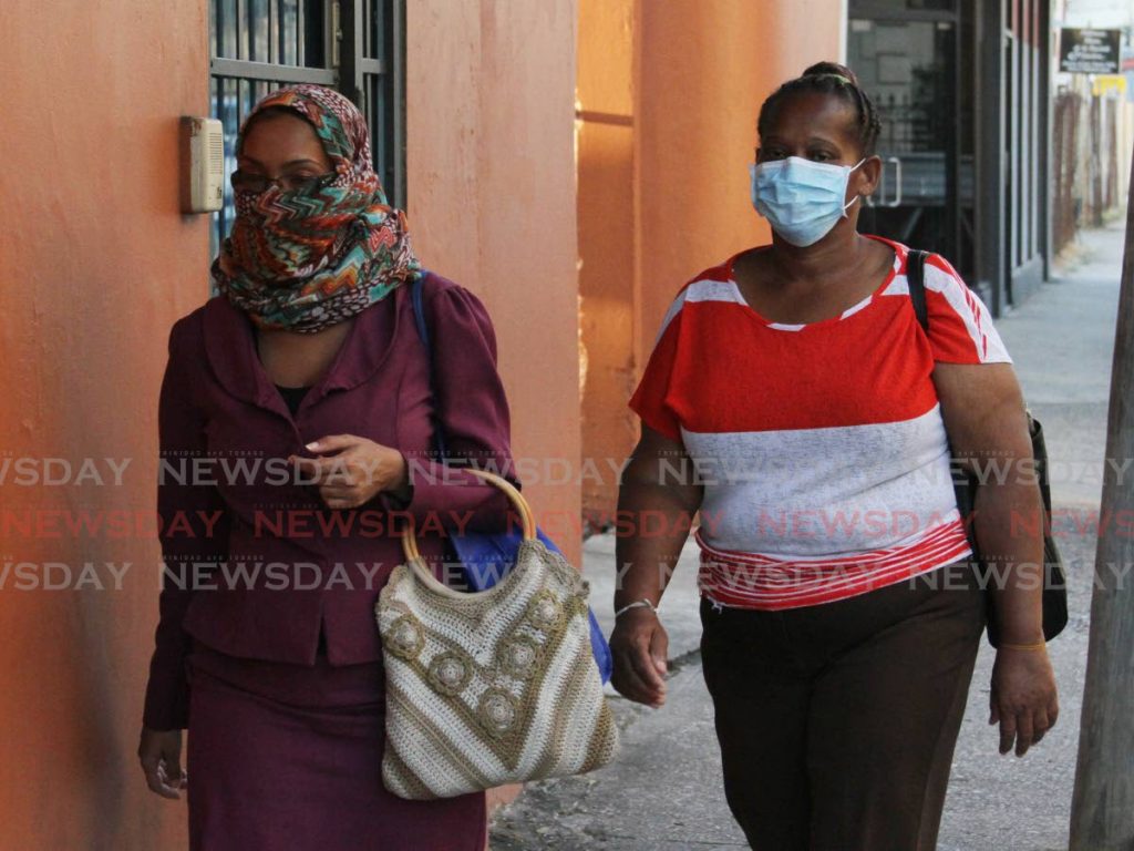 COVERED UP: Amid national unease over the coronavirus, these women covered their faces, one with a head scarf and the other with a face mask as they walked along Pembroke Street in Port of Spain. - Angelo Marcelle