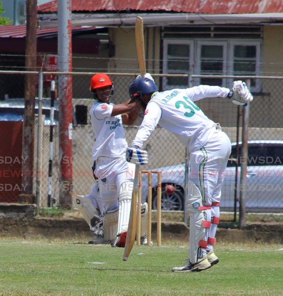Crystian Thurton of St Benedict’s College, hits a boundary to bring up his half century, almost striking his team-mate Rodney Sieunarine, during the PowerGen Secondary Schools Cricket League match versus Fatima College at Fatima grounds, Mucurapo Road, St James, on Tuesday. 
 - ROGER JACOB