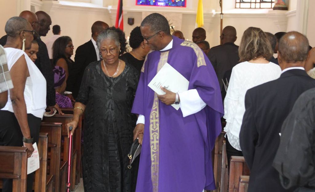 Fr Gregory Augustine walks with Jeanette Hayfron-Benjamin, sister of Althea Bastien at St Ann’s RC Church, St Ann’s on Thursday. Artist and fashion desginers hail Bastien, who died on March 4 at 86, as a pioneer of batik art. PHOTO BY AYANNA KINSALE - 