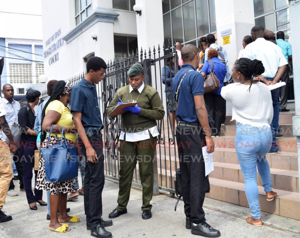 A security officer takes information from members of the public during a covid19 screening exercise at the Magistrates Court, St Vincent street, Port of Spain, on Monday. - Vidya Thurab