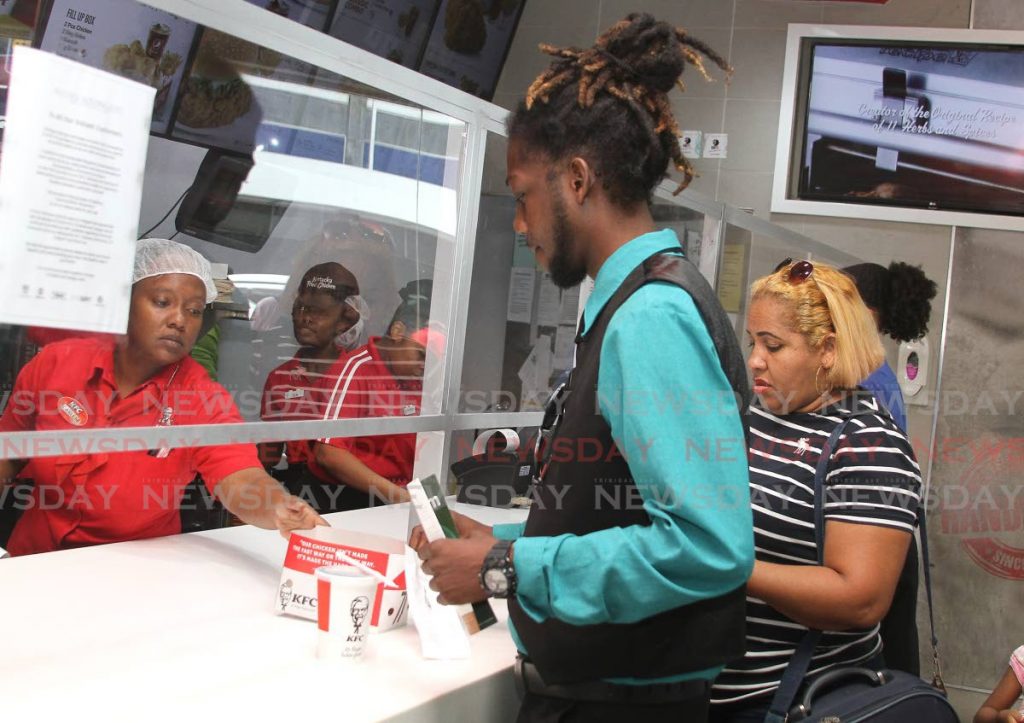 In this March 16 file photo, a customer buys a meal at KFC, Independence Square, Port of Spain where an enclosure was put in place as a precaution against the spread of covid19. - Ayanna Kinsale