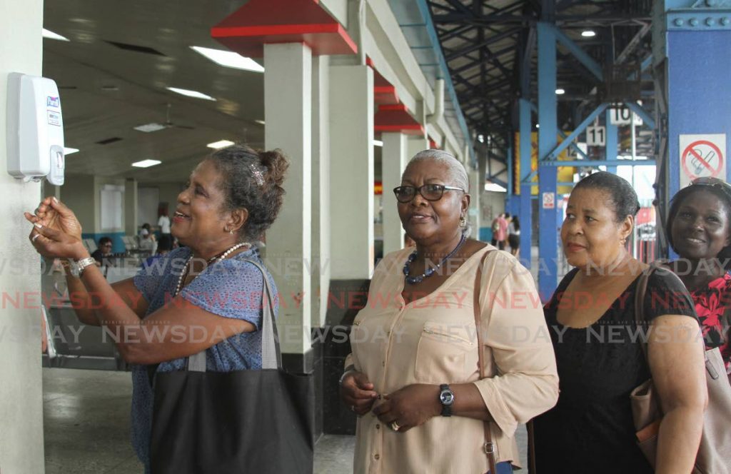 In this file photo, passengers at City Gate, Port of Spain use hand sanitizer provided by the Public Transport Service Corporation (PTSC)  in an effort to prevent the spread of the coronavirus.   Ayanna Kinsale