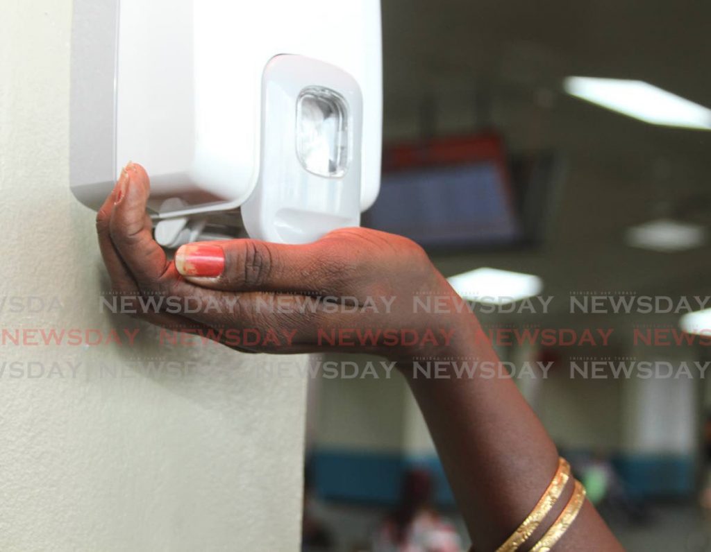 A passenger uses hand sanitizer provided by the Public Transport Service Corporation (PTSC) at City Gate a measure being encouraged to prevent the spread of the covid19. - Ayanna Kinsale
